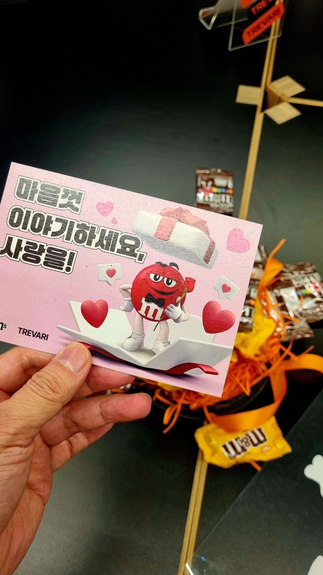 M&M 캐릭터가 그려진 트레바리 발렌타인 엽서를 손에 든 모습